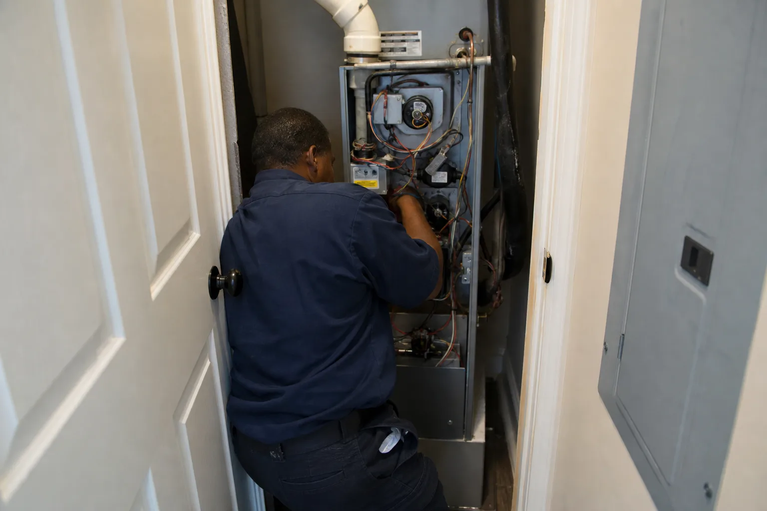 Technician inspecting a furnace in a Charlotte home